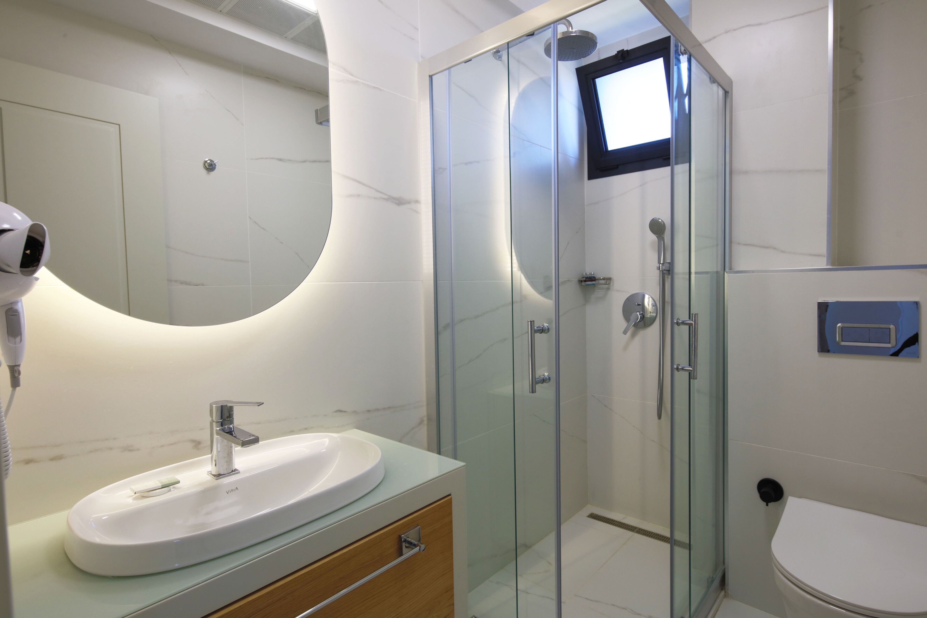 Un baño moderno con ducha envuelta en vidrio, un lavabo blanco y un espejo.