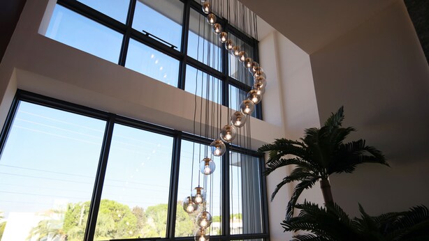 Un interior moderno con ventanas amplias, un elemento decorativo de iluminación y una planta en maceta.