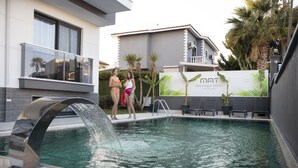 Una piscina con fuente, un edificio con balcón y un letrero que dice Boutique Hotel.