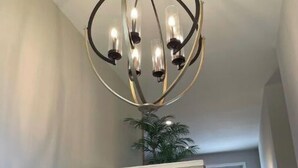 Ein Kronleuchter mit mehreren Lichtern, eine Wanddekoration als Anker und eine Treppe zu einem anderen Raum.