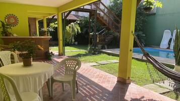 A patio area with a table and chairs, a pool, and a staircase leading to a garden.