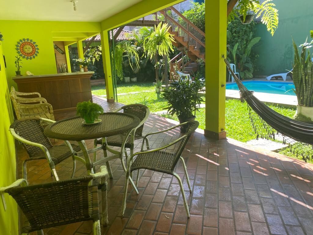 Un patio con mobiliario de mimbre, una pequeña mesa redonda y una piscina al fondo.