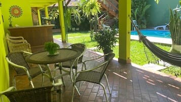 Un patio con mobiliario de mimbre, una pequeña mesa redonda y una piscina al fondo.