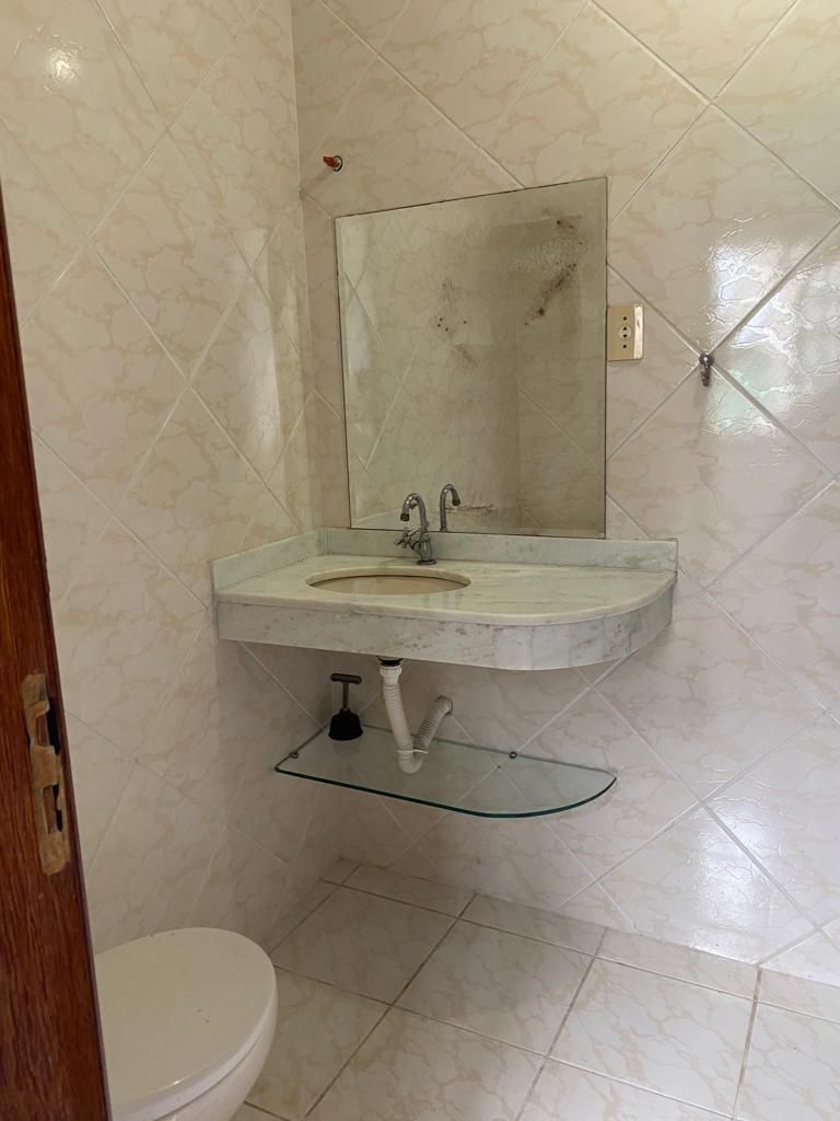 Et badeværelse med en marmorvask, en glashylde og et hvidt toilet.