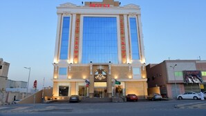 A hotel with a large glass facade, a prominent entrance with a decorative arch, and the name 'HOTEL' displayed above. - Crown City Hotel (Riyadh)