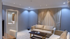Una sala de estar moderna con un sofá color beige, una mesa de centro de madera y un televisor sobre un mueble.