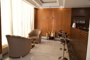 A modern coffee shop interior with a wooden wall, a bar counter, and seating area. - Crown City Hotel (Riyadh)