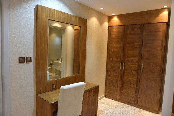 A bedroom with a wooden wardrobe, a bedside table, and a mirror.
