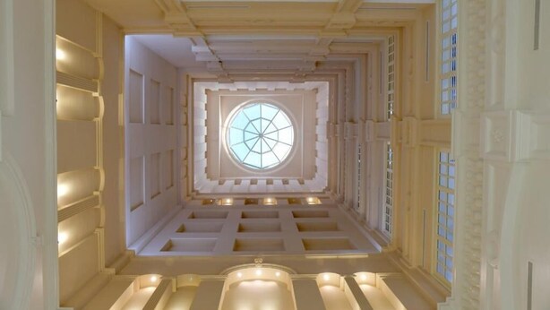 Una gran escalera simétrica con un ventanal circular central, rodeada de detalles arquitectónicos ornamentales.