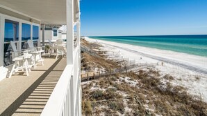 A beachfront property with a covered patio area, outdoor seating, and a view of the beach and ocean.