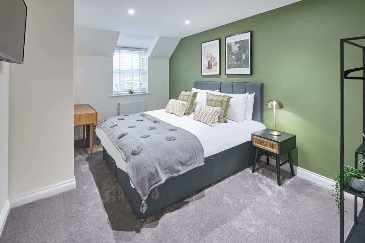 A bedroom with a bed, bedside table, lamp, and a window.