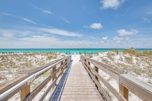 A wooden boardwalk leading to a beach with clear skies.
