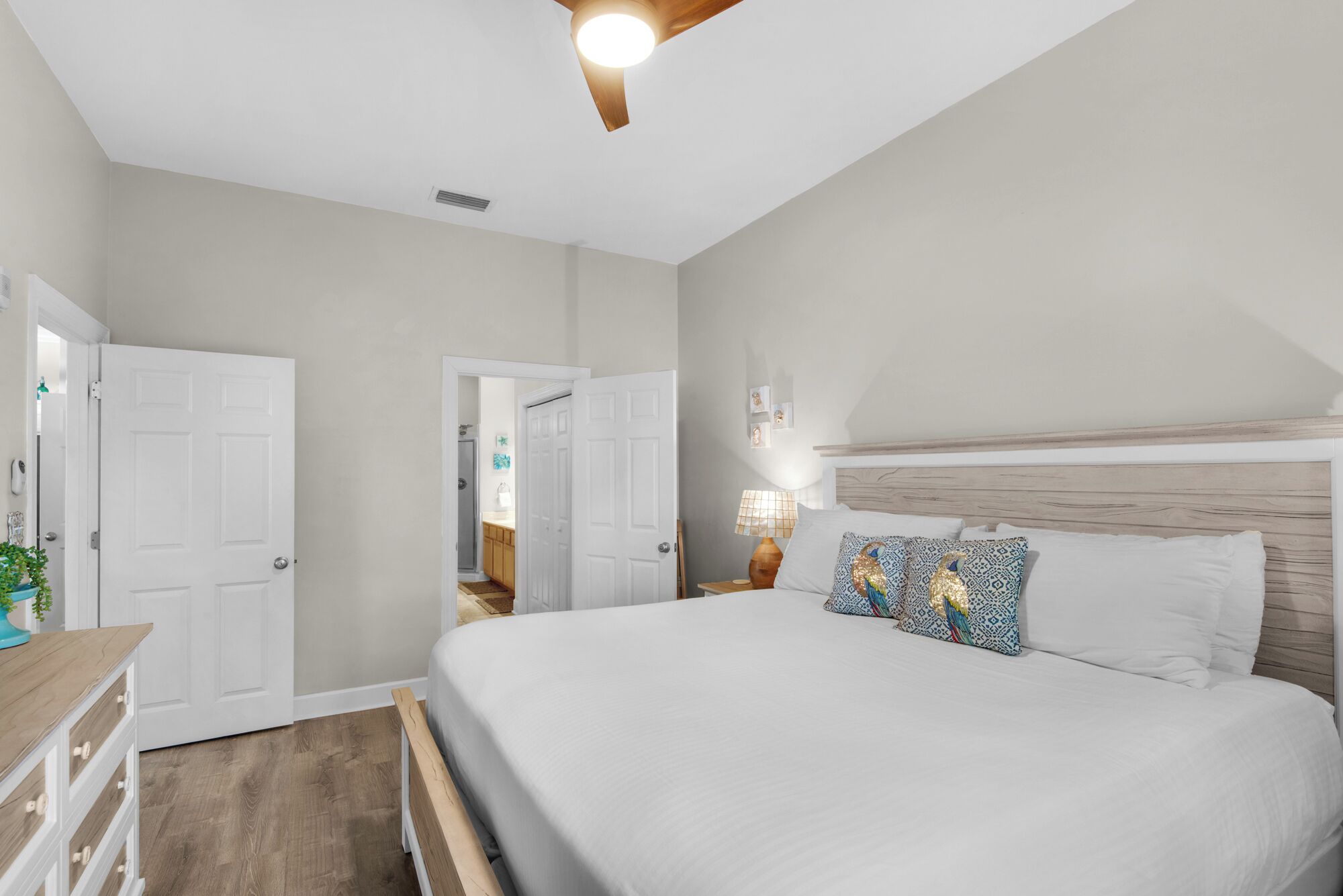 Un dormitorio con una cama grande, un cabecero de madera, una mesita de noche con una lámpara y una puerta que da a un baño.