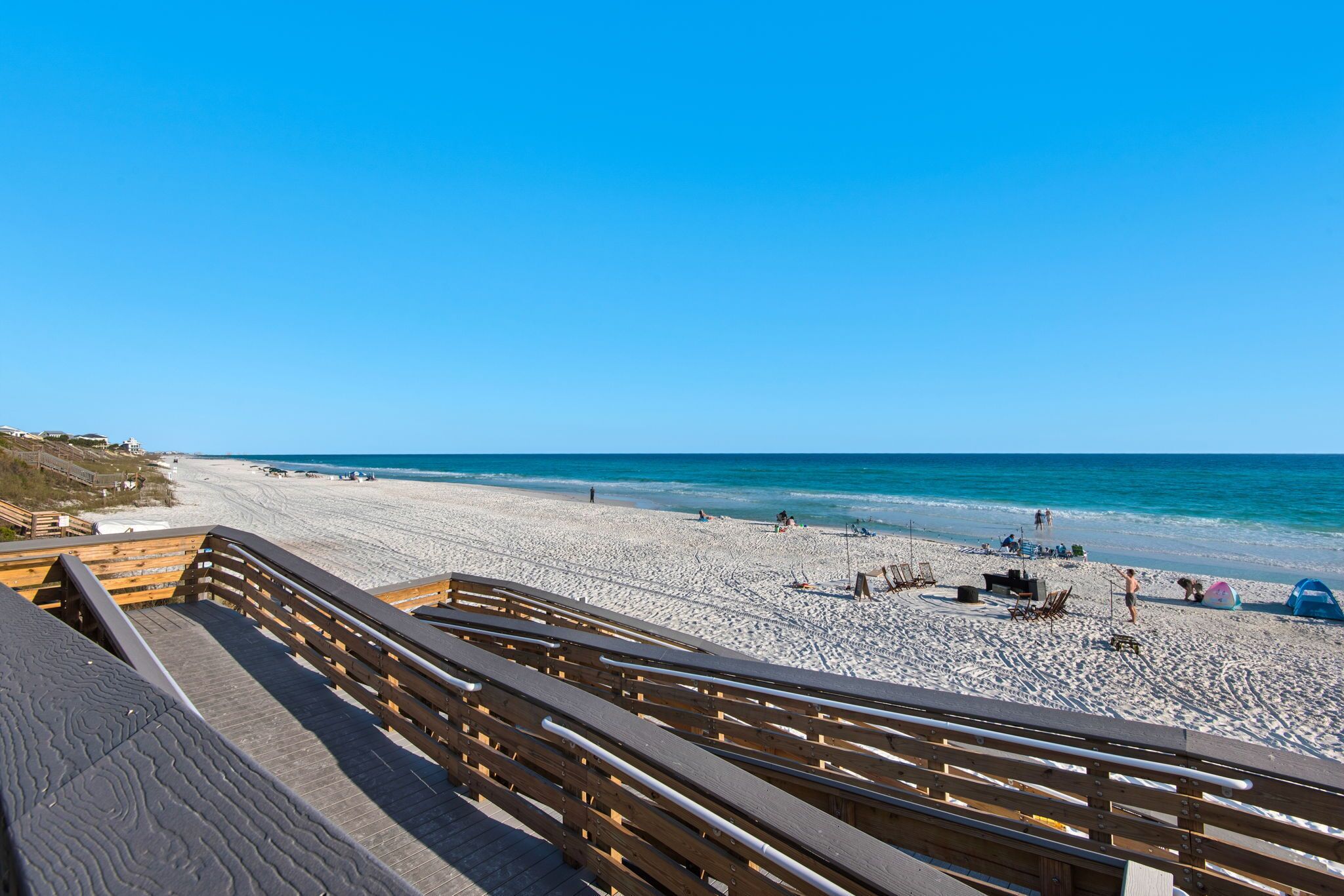 A beach with a wooden boardwalk leading to the shore, sandy beach, and the ocean.