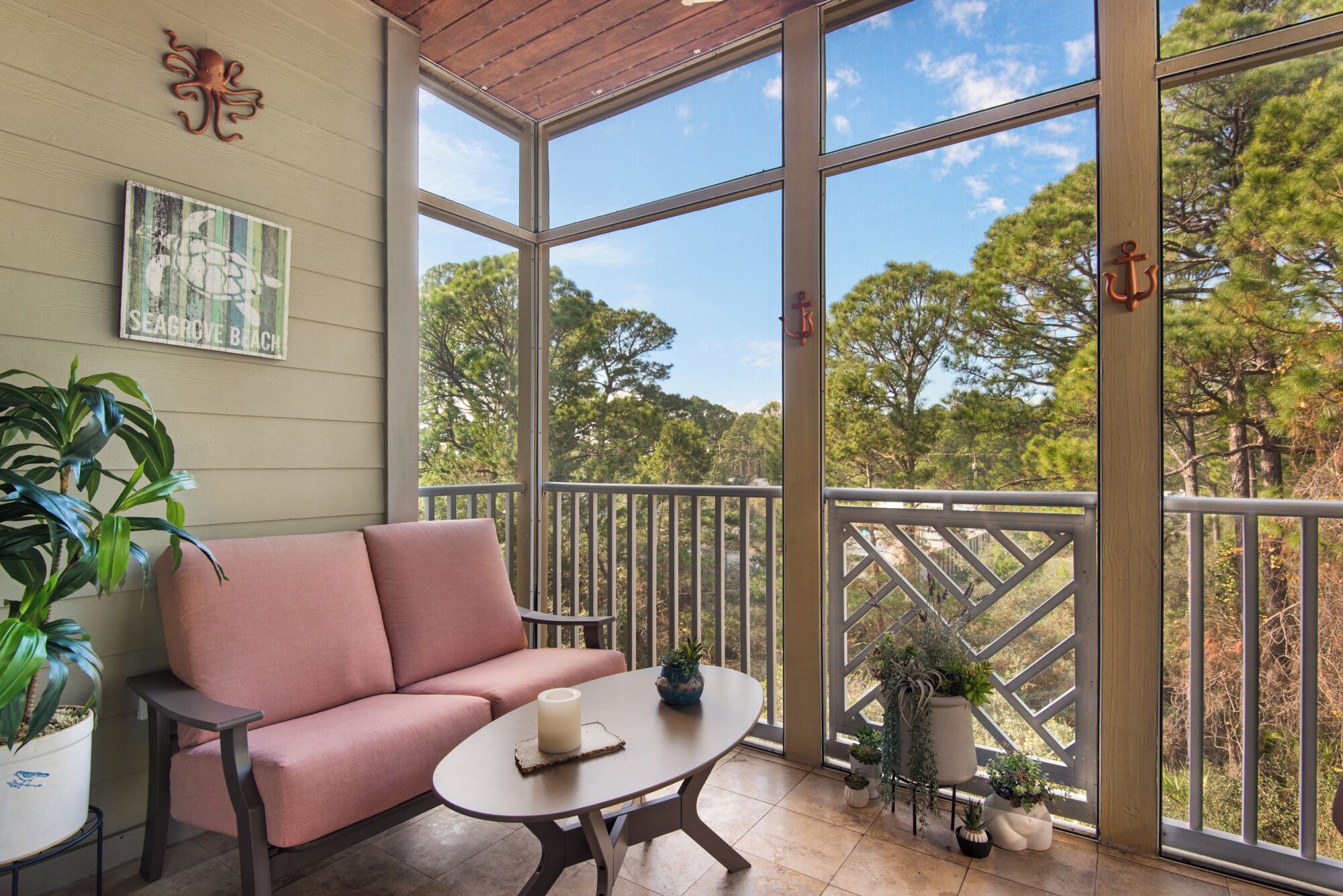 A balcony with a cushioned seating area, a small table, and potted plants.