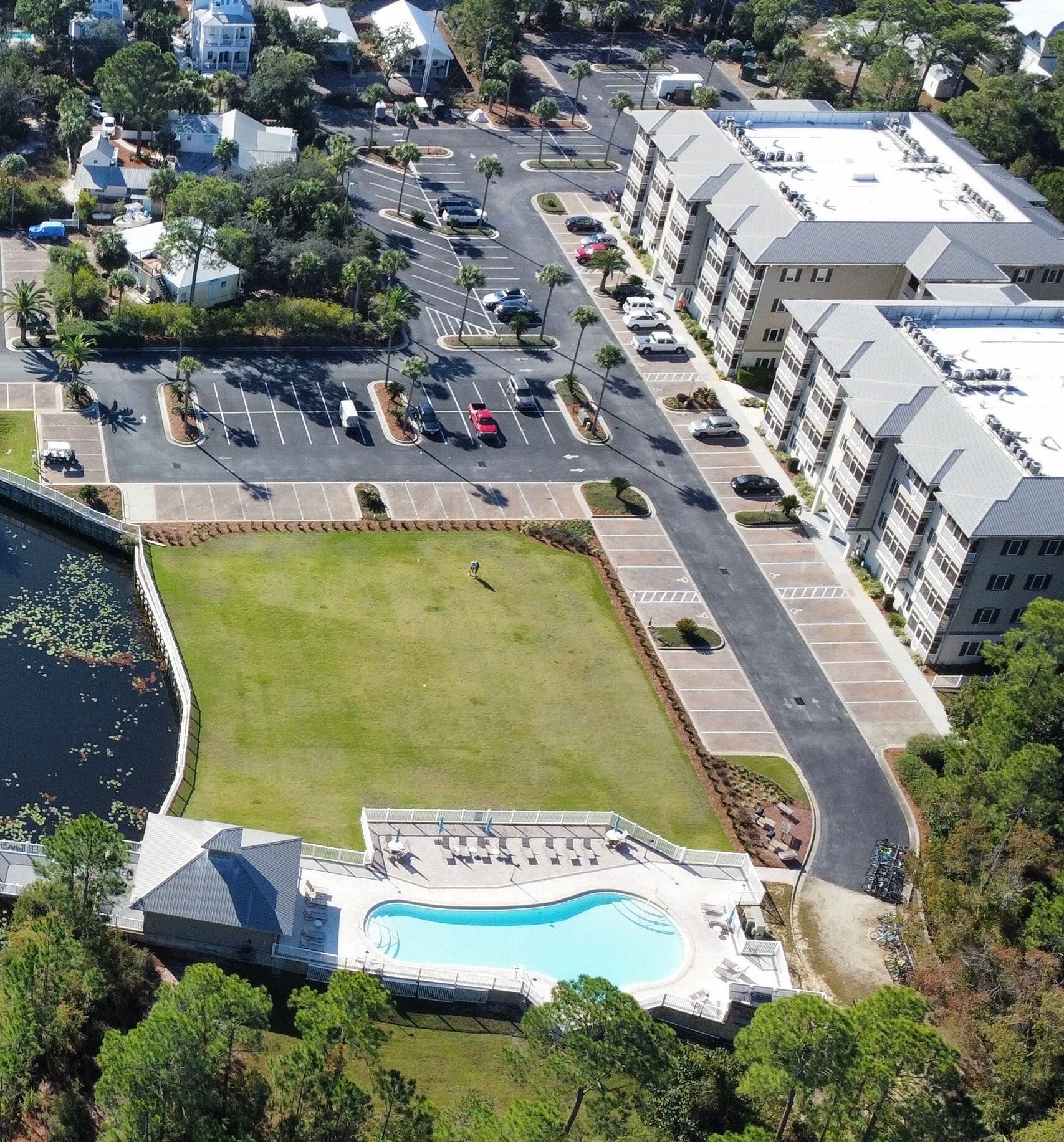 An aerial view of a residential area with a swimming pool, parking lot, and apartment buildings.