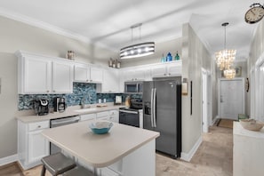 A modern kitchen with white cabinets, a stainless steel refrigerator, a coffee maker, and a blue bowl on the counter.