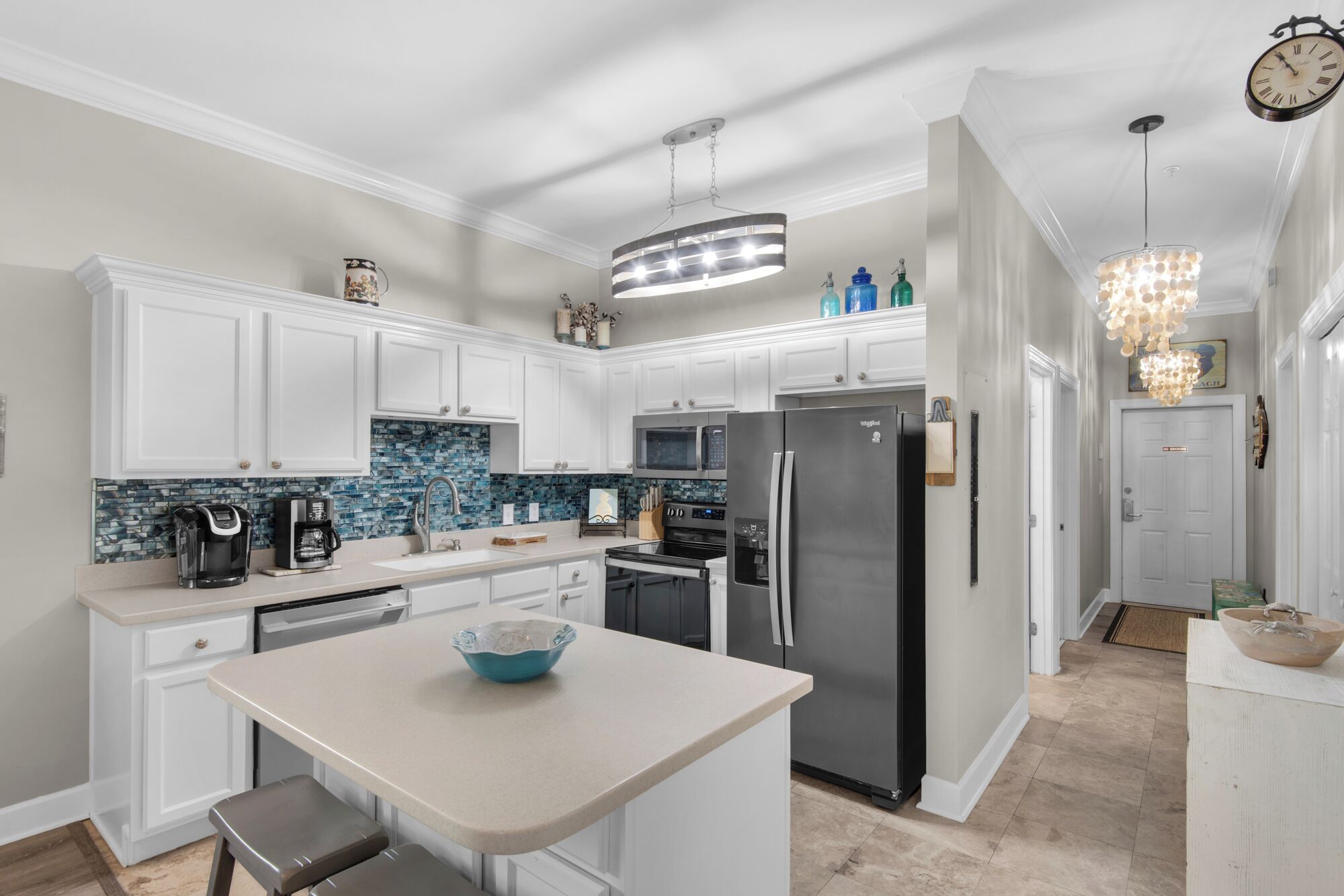 A modern kitchen with white cabinets, a stainless steel refrigerator, a coffee maker, and a blue bowl on the counter.