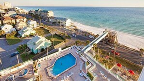 Vista aérea de una zona costera con piscina, playa y edificios residenciales.