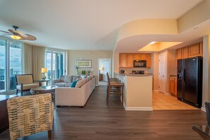 A modern apartment with a living room, dining area, kitchen, and a balcony with a view.