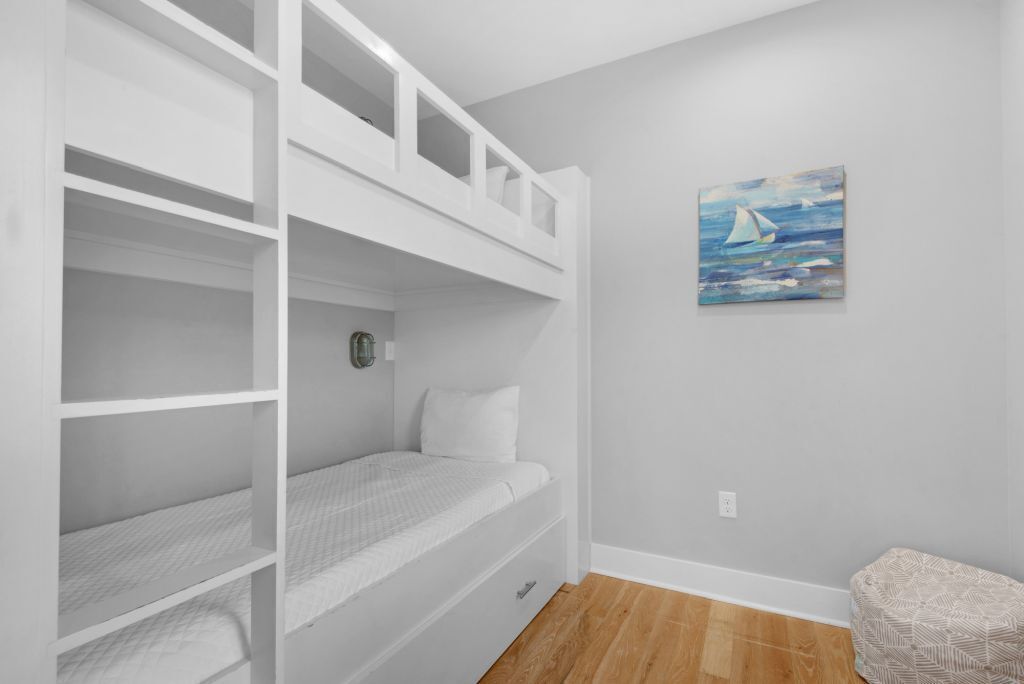 Une chambre avec un lit superposé, une petite table de chevet et une horloge fixée au mur.