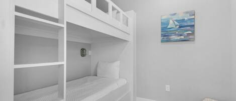Une chambre avec un lit superposé, une petite table de chevet et une horloge fixée au mur.
