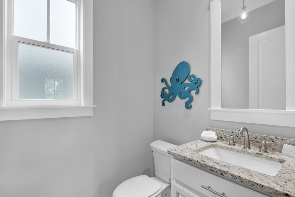 Un bany amb un vàter blanc, un lavabo amb taulell de granat i una decoració d'pop blau a la paret.