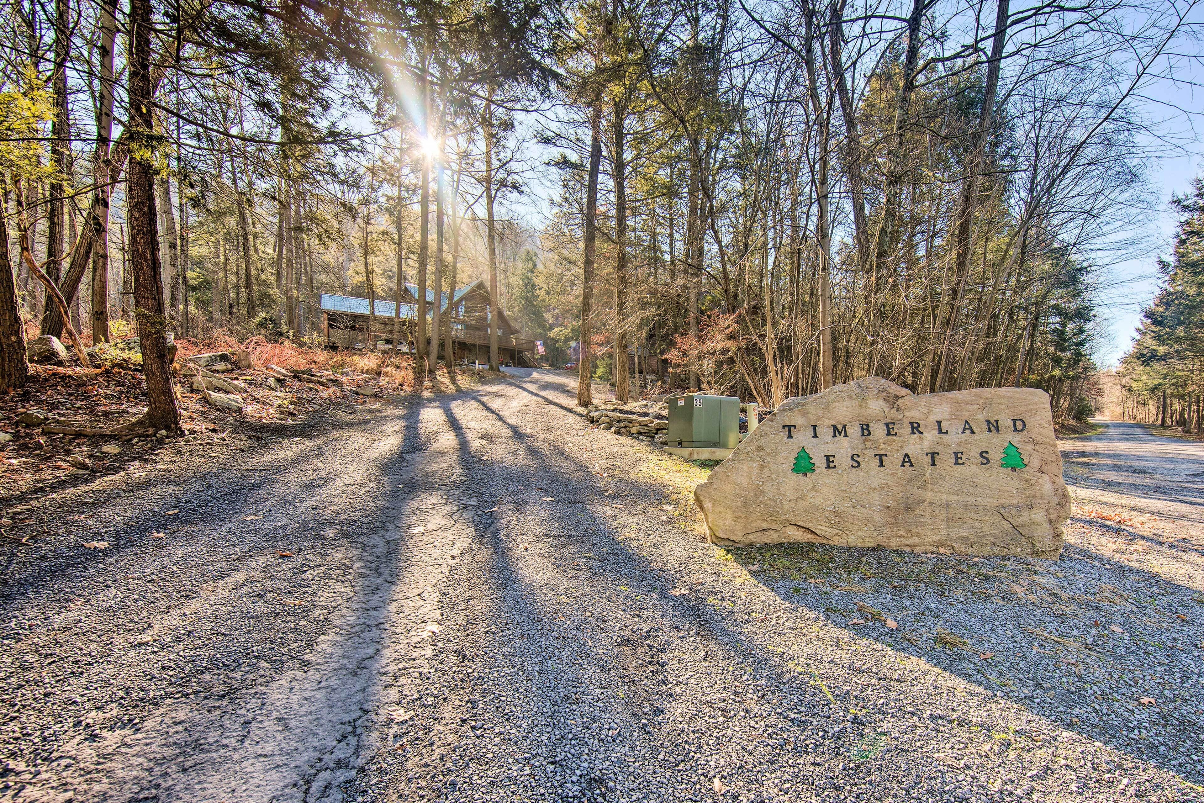 Un sendero de grava que lleva a una cabaña con un letrero que dice "Timberland Estates".