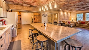 Een ruime keuken met een groot kookeiland, barstoelen en een rustiek plafond.
