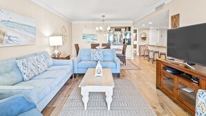 Un salon spacieux avec un canapé bleu, une table basse et un téléviseur posé sur un meuble en bois.