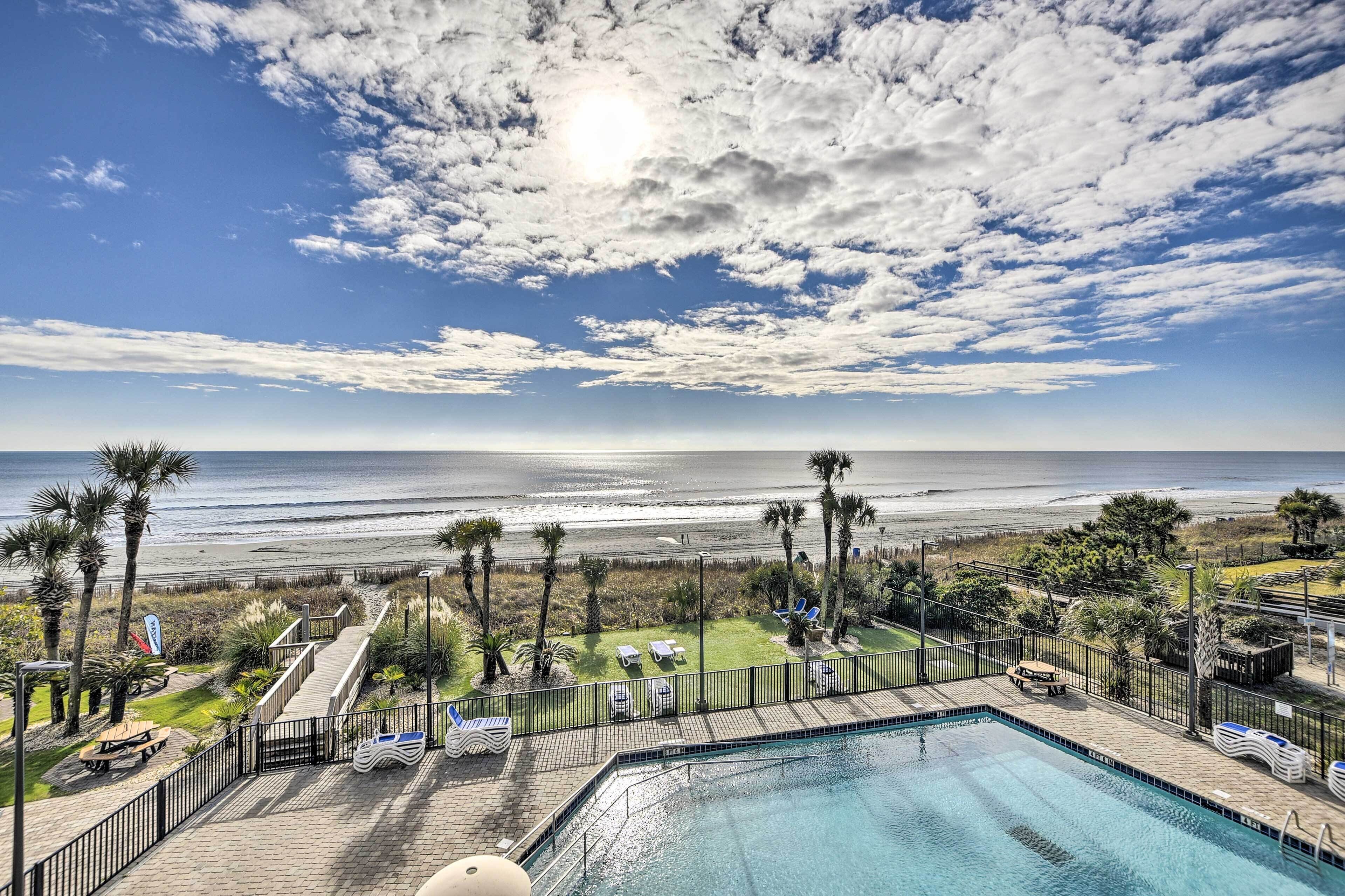 A pool area with a view of the beach and ocean.