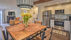 Una cocina moderna con armarios blancos, electrodomésticos de acero inoxidable y una mesa de comedor de madera con individuales.