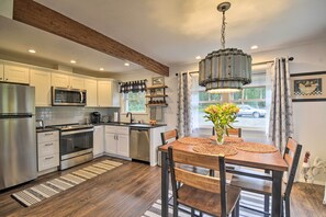 A modern kitchen with white cabinets, stainless steel appliances, and a wooden dining table with placemats.