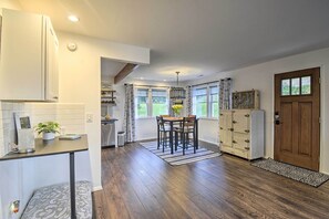 A kitchen with a dining area, wooden flooring, and a view of the outdoors.