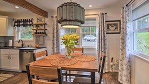 Un comedor con una mesa de madera, individuales tejidos y una lámpara colgante.