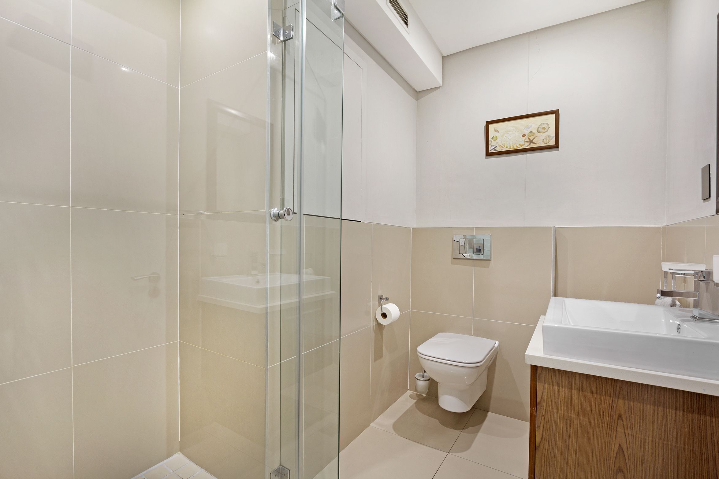 Une salle de bain moderne avec une douche à parois de verre, des toilettes et un lavabo avec un meuble en bois.