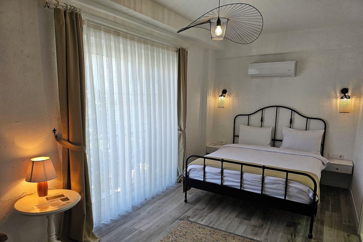 A bedroom with a bed, bedside tables, a lamp, a ceiling fan, and a window with curtains.