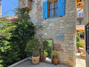 A stone building with a wooden balcony, a potted plant, and a sign indicating directions to a pool and garden. - Kugu Urla  (Urla)
