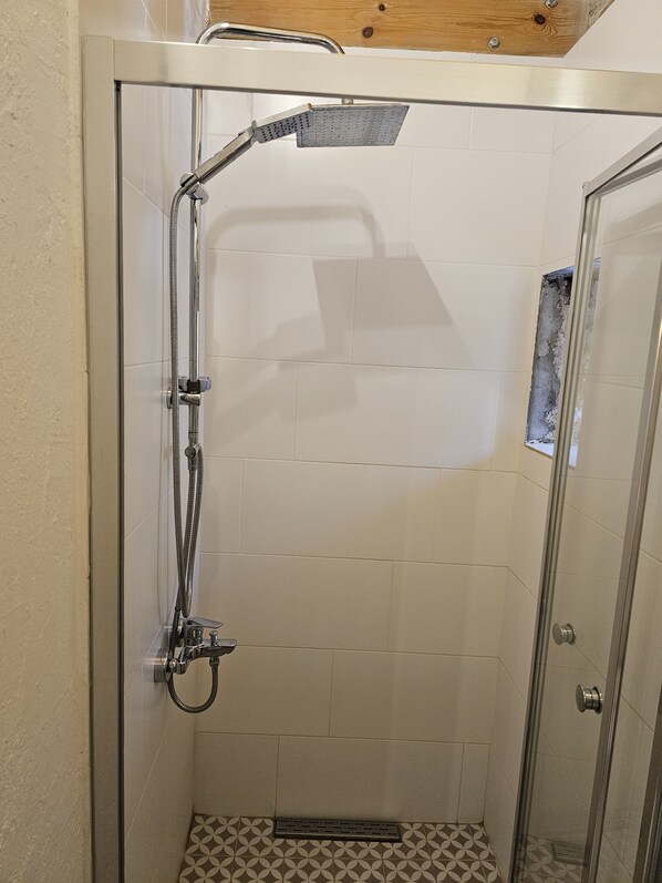A glass-enclosed shower with a handheld showerhead and a fixed showerhead. - Kugu Urla (Urla)