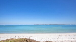 A beach with clear blue water and a sandy shore.