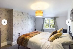 A bedroom with a bed, a window with curtains, a wall with a deer pattern, and a hanging light fixture. - Beautiful Farmhouse set in Lincolnshire countryside (Market Rasen)
