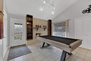 Taula de bitlles en una habitació amb paret de maó, prestatges i una porta amb panell de vidre.