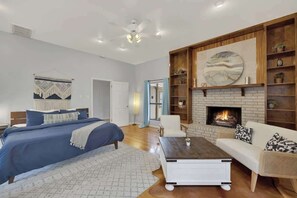 Un salon moderne avec une cheminée, un canapé, une table basse et un lit avec une literie bleue.