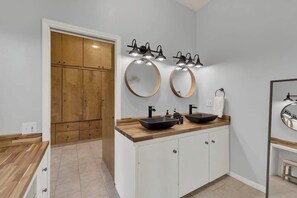 Een moderne badkamer met twee wasbakken, een houten wastafelmeubel en een grote spiegel.