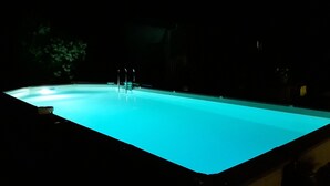 A swimming pool at night with clear water and a ladder. - Chambres d'hôtes de l'île du saule (Saumur)