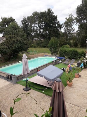 A backyard with a swimming pool, outdoor furniture, and a lawn.