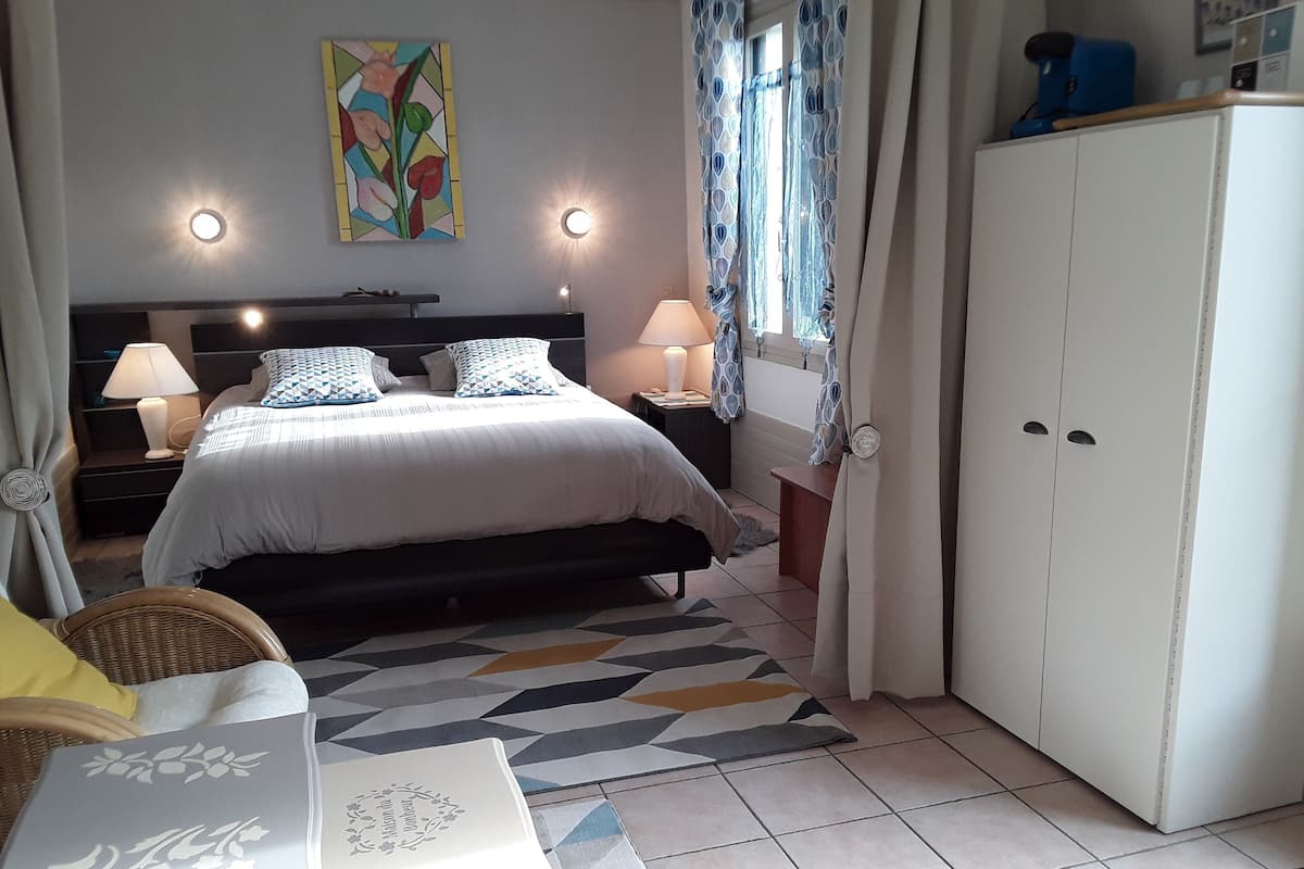 A bedroom with a bed, bedside tables, a nightstand, a wardrobe, and a chair.