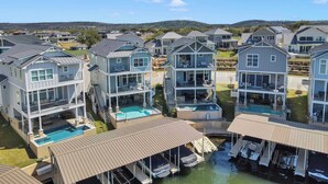 A coastal residential area with multi-story houses featuring balconies, swimming pools, and a marina.