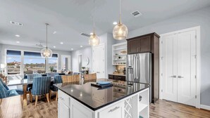 A modern kitchen with a central island, white cabinetry, and stainless steel appliances.