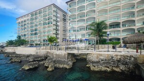 Un hotel a più piani con balconi, una zona piscina e vista sull'oceano.